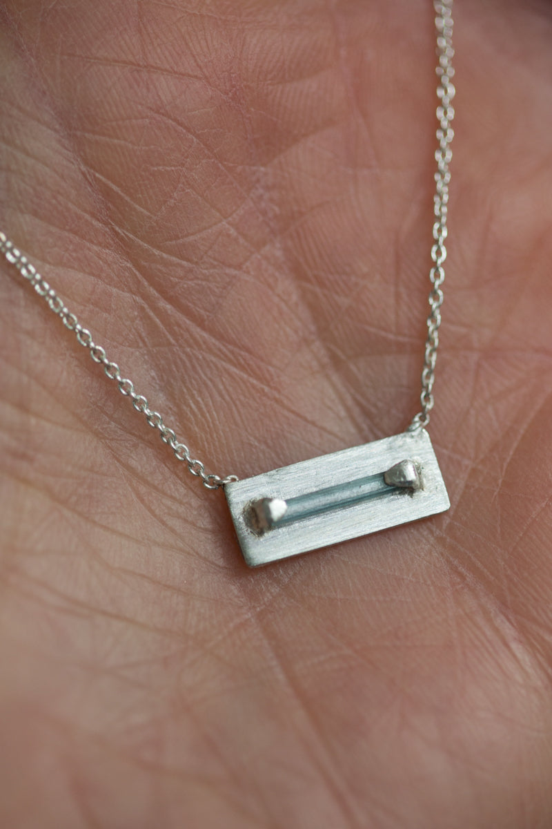 Handgemaakt zilveren kettinkje met een geometrische hanger een toermalijn staafje. 