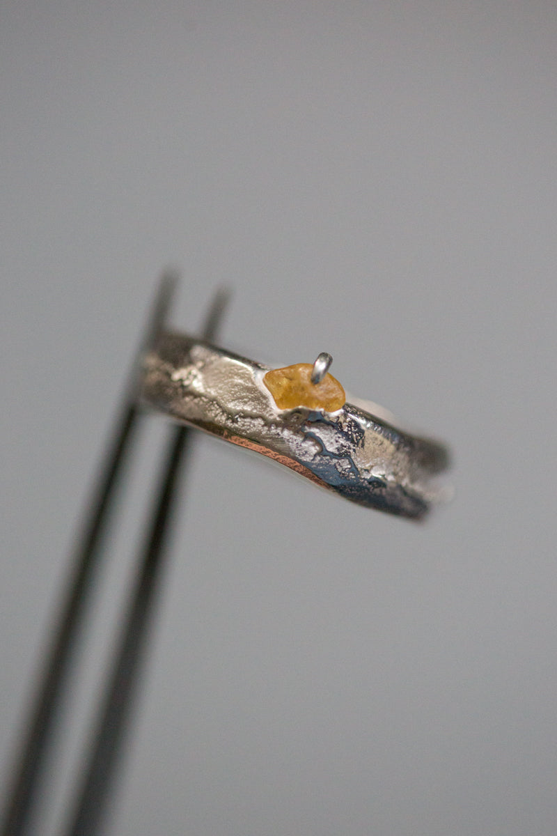 Handgemaakte en fairtrade zilveren sand cast ring met cast in place ruwe saffier