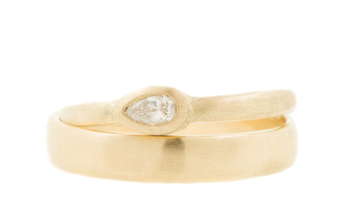 Matte trouwringen met hamerslag van 14 kt fairtrade geelgoud en een peervormige diamant
