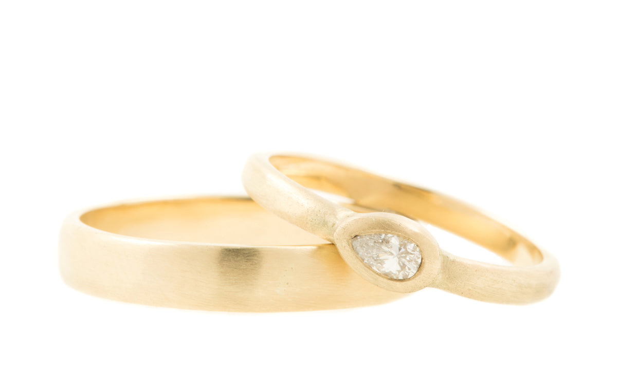 Matte trouwringen met hamerslag van 14 kt fairtrade geelgoud en een peervormige diamant