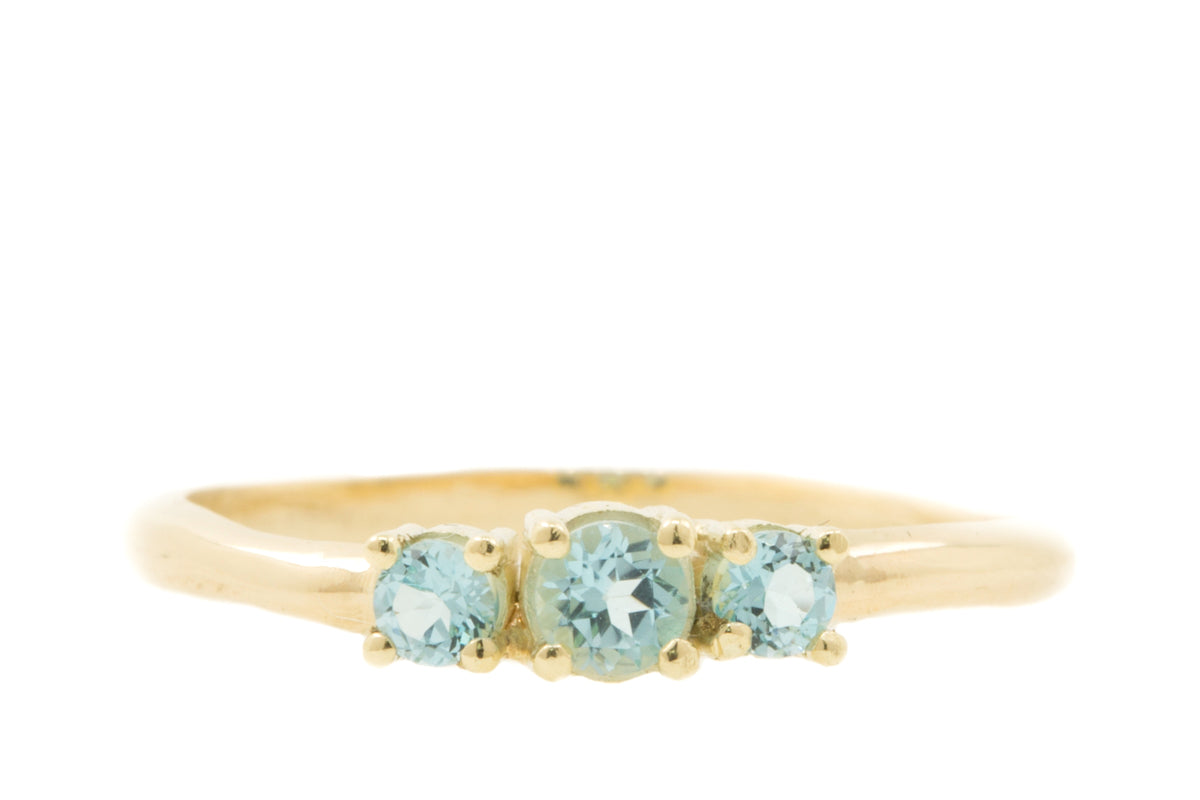 Handgemaakte en fairtrade fijne licht organische gouden ring met drie lichtblauwe topazen