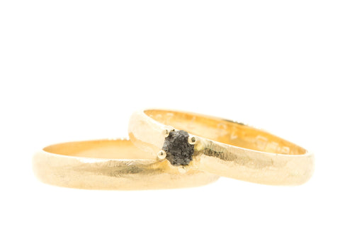 Handgemaakte en fairtrade ruwe trouwringen van geelgoud met donkere ruwe diamant